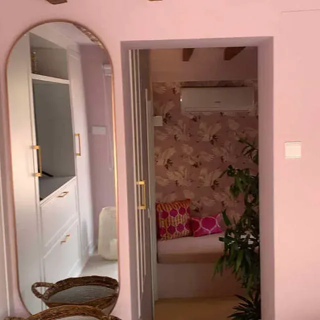 Una habitación con paredes rosas y un gran espejo en la pared.