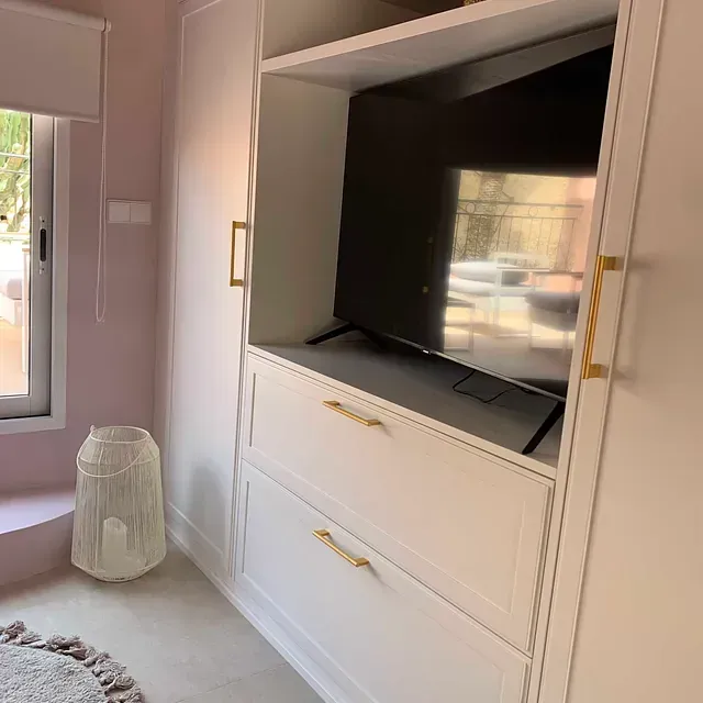 Un televisor está encima de una cómoda blanca en una habitación.