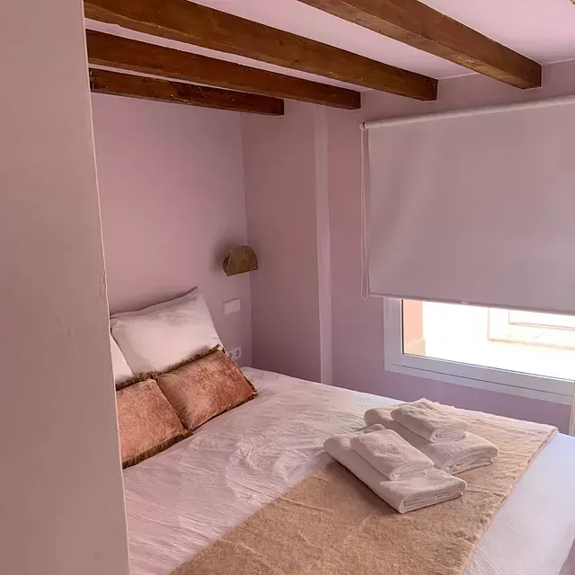 Un dormitorio con una cama, ventana y toallas en la cama.
