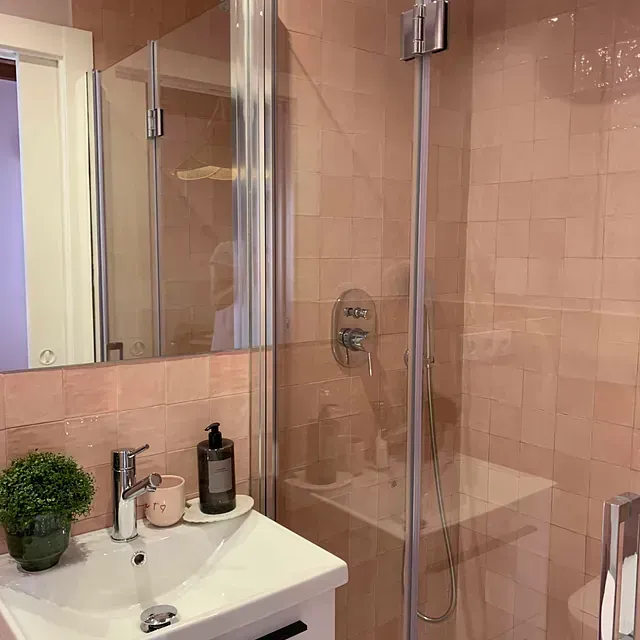 Un baño con lavabo, inodoro, ducha y espejo.