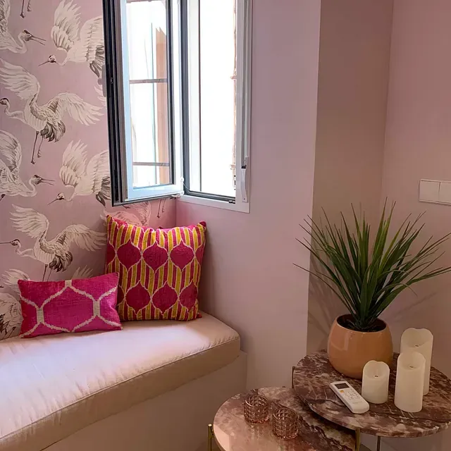 Un asiento junto a la ventana con almohadas y velas delante.