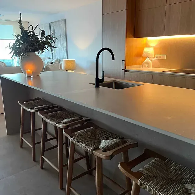 Una cocina con taburetes y un fregadero en la encimera.