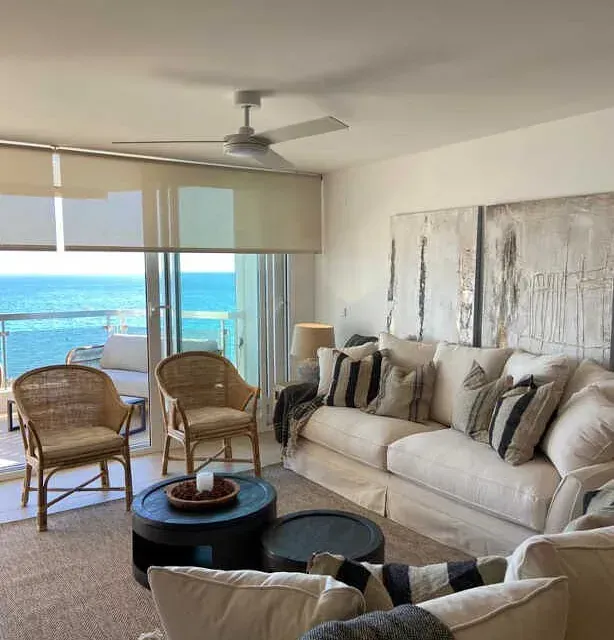 Una sala de estar con sofá y sillas con vista al mar.