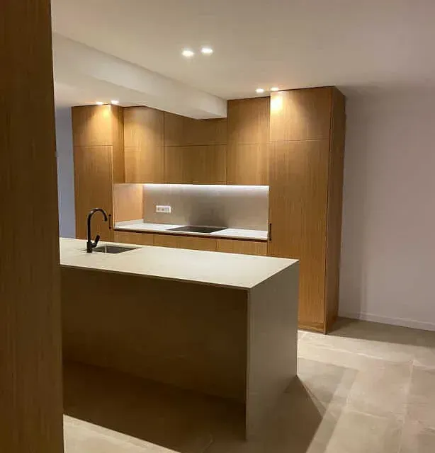 Una cocina con muebles de madera y una gran isla con fregadero.