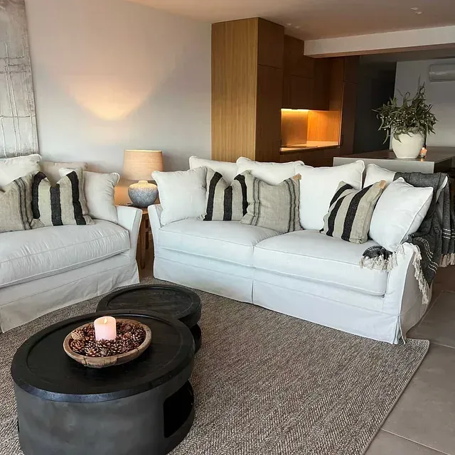 Una sala de estar con dos sofás blancos y una mesa de café redonda.