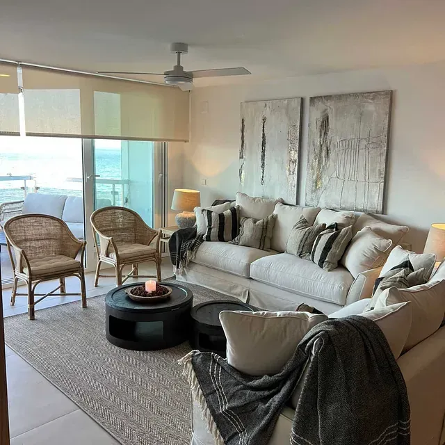 Una sala de estar con un sofá y sillas y un ventilador de techo.