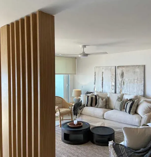 Una sala de estar con un sofá, sillas, mesas y un ventilador de techo.