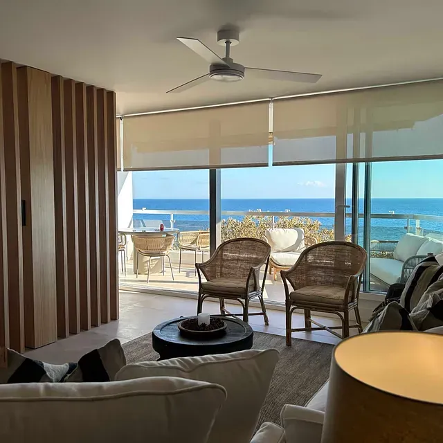 Una sala de estar con ventilador de techo y vista al mar.