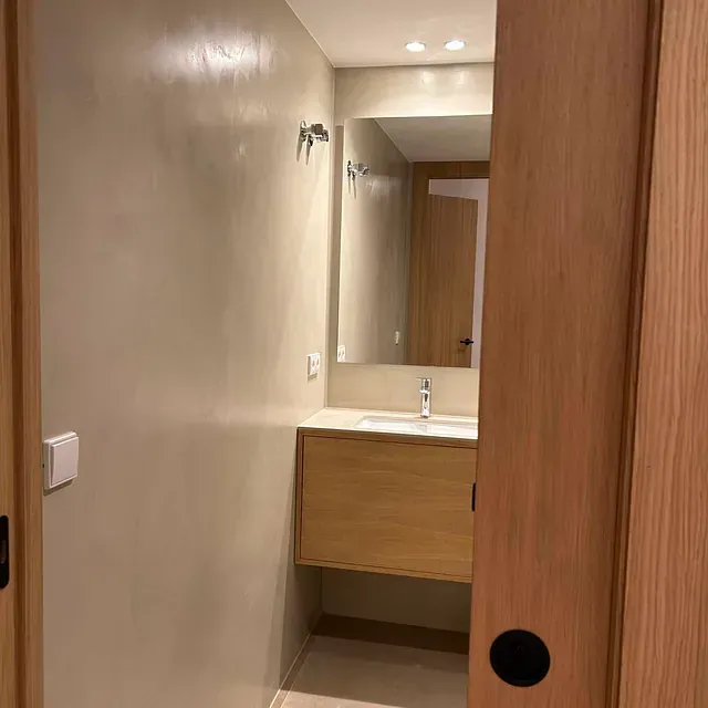 Un baño con lavabo, espejo y puerta corredera.