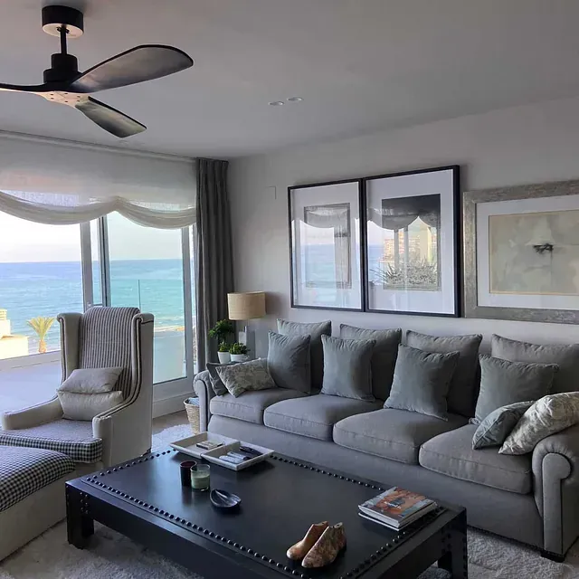 Una sala de estar con ventilador de techo y vista al mar.