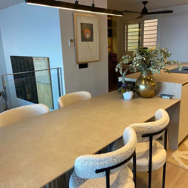 Una mesa de comedor con sillas y un jarrón de flores encima.