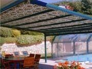 Un patio con una mesa y sillas bajo un dosel con vistas a una piscina.