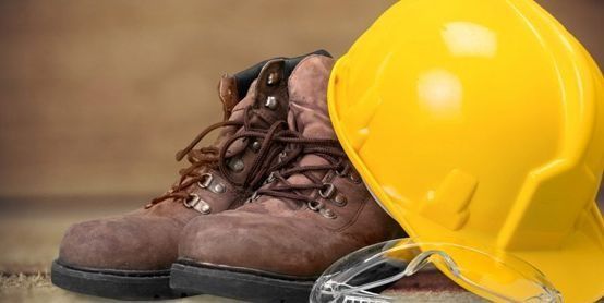 Un par de botas, un casco y gafas de seguridad están sobre una mesa.