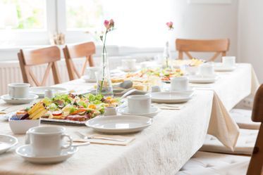 Ein langer Tisch mit Tellern, Tassen und Untertassen darauf.