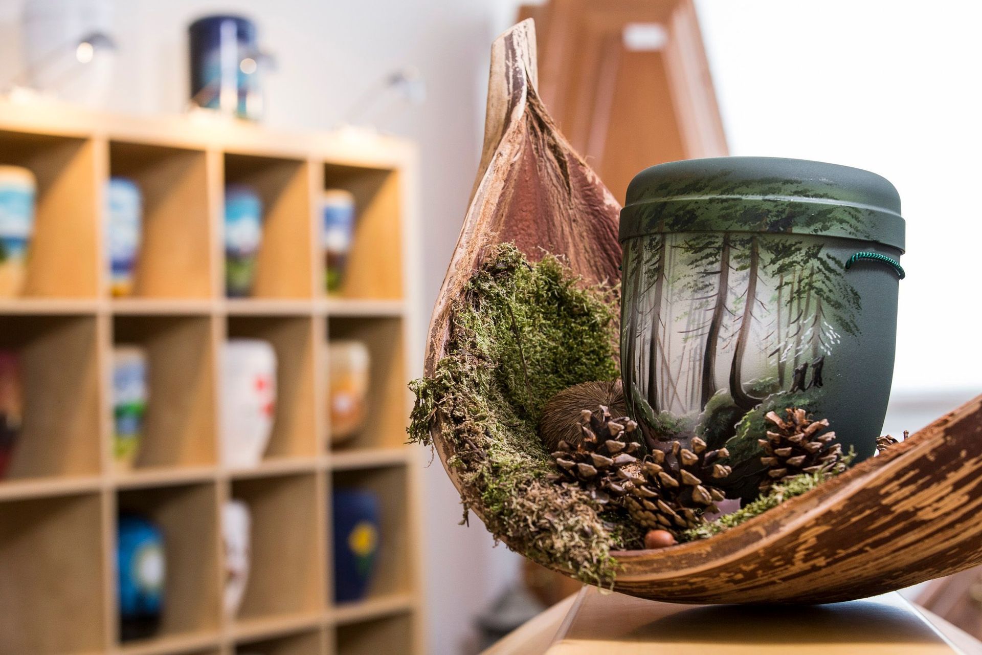 Auf einem Holztisch steht eine Urne mit Tannenzapfen.