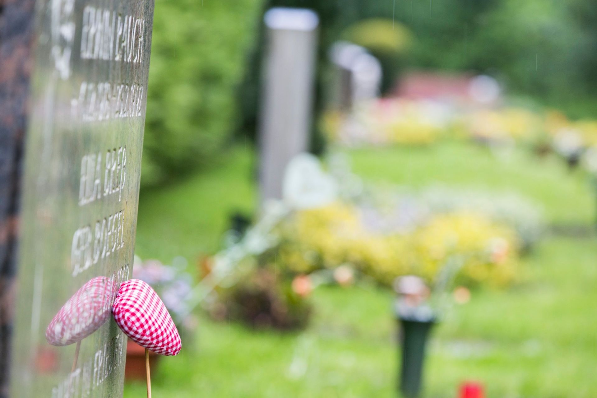 Ein Friedhof mit einem Grabstein und Blumen im Gras.