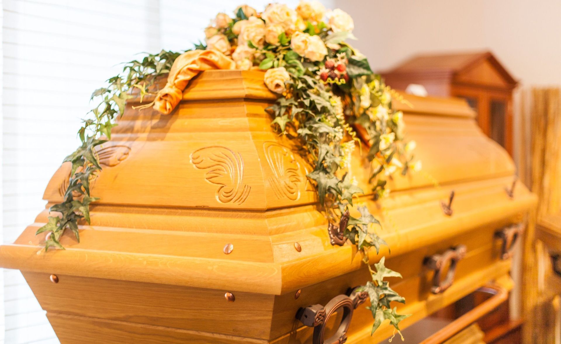 Ein Holzsarg mit Blumen darauf in einem Raum.