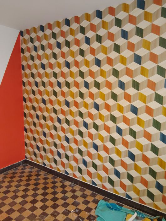 Papier peint géométrique dans une pièce avec un mur, un sol à damier et un tissu par terre.