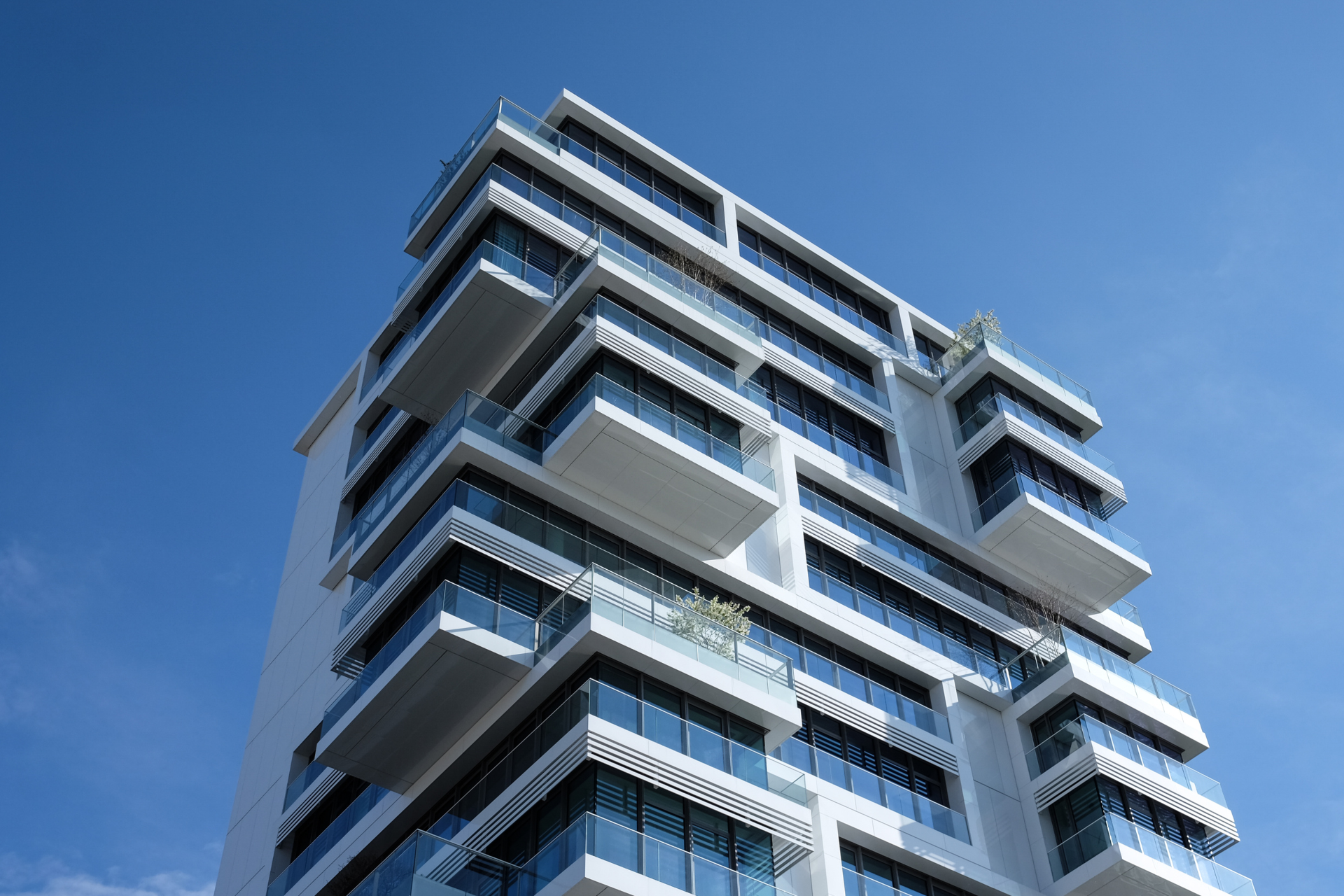 Edificio de apartamentos moderno de color blanco con balcones contra un cielo azul claro.