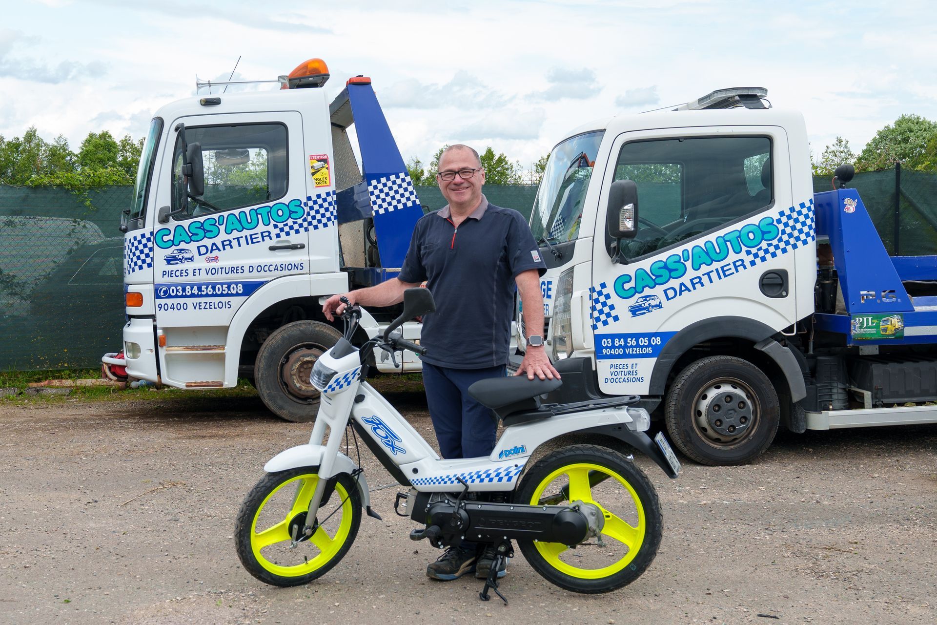 Remorqueuses et dirigeant de la casse auto tenant une mobylette floquée