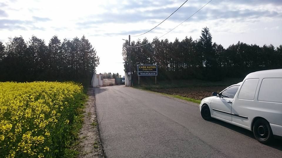 Véhicule sur une route avec un panneau Cass'Auto Dartier