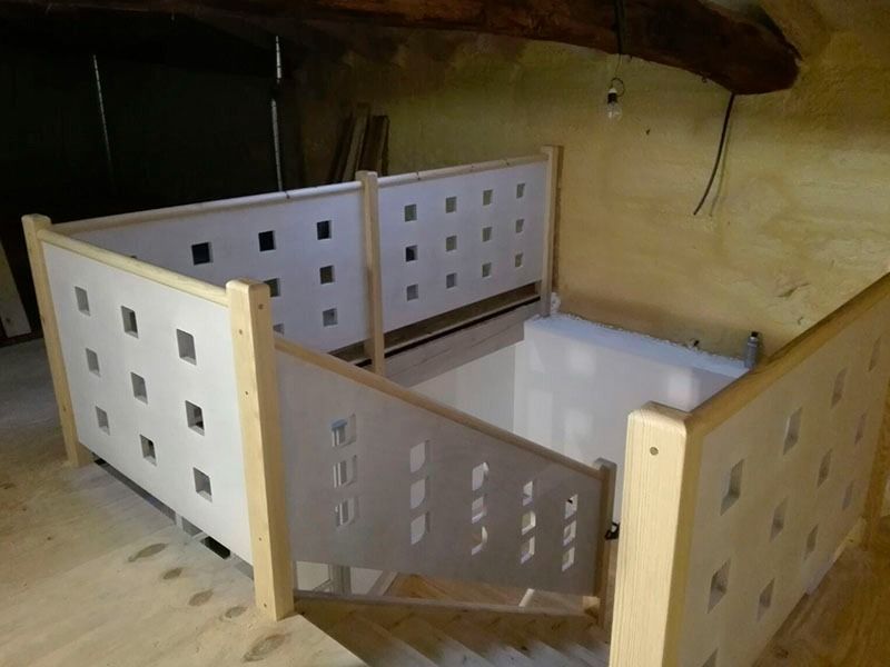 Una escalera con barandilla de madera y una valla blanca.