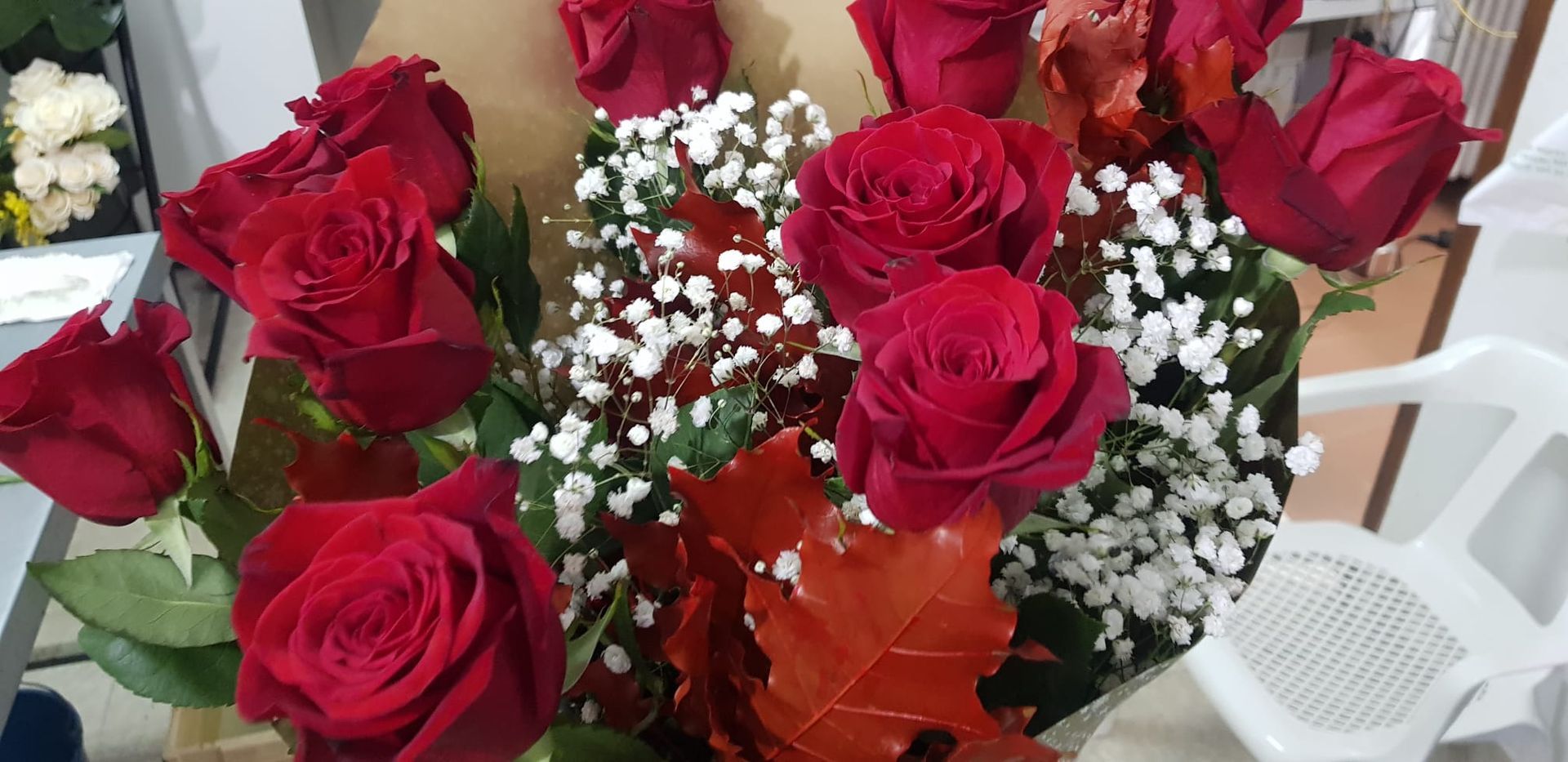 Un jarrón lleno de rosas rojas y flores de bebé está sobre una mesa.