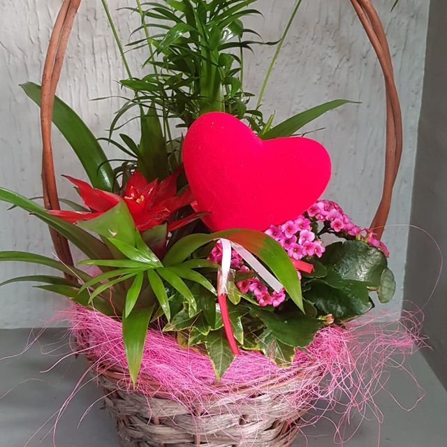 Una cesta llena de flores y un corazón rojo.