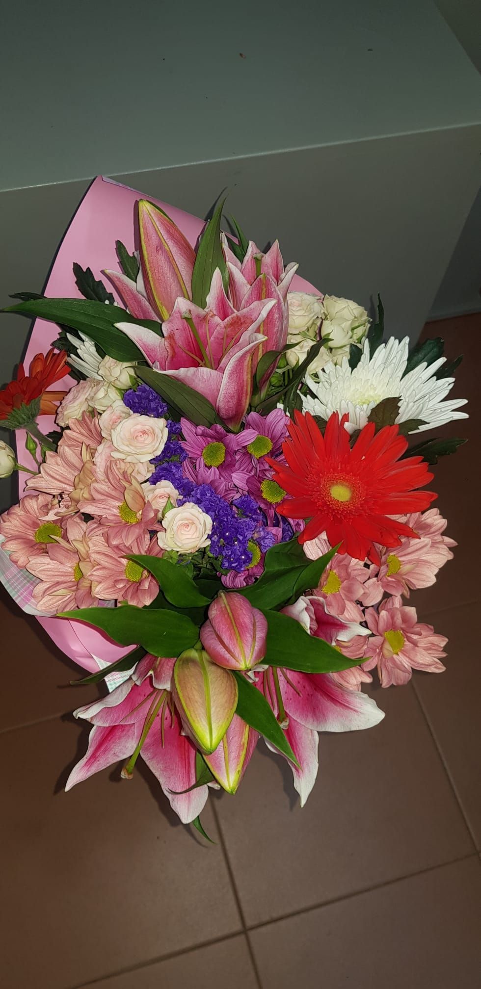 Un ramo de flores está sobre un suelo de baldosas.