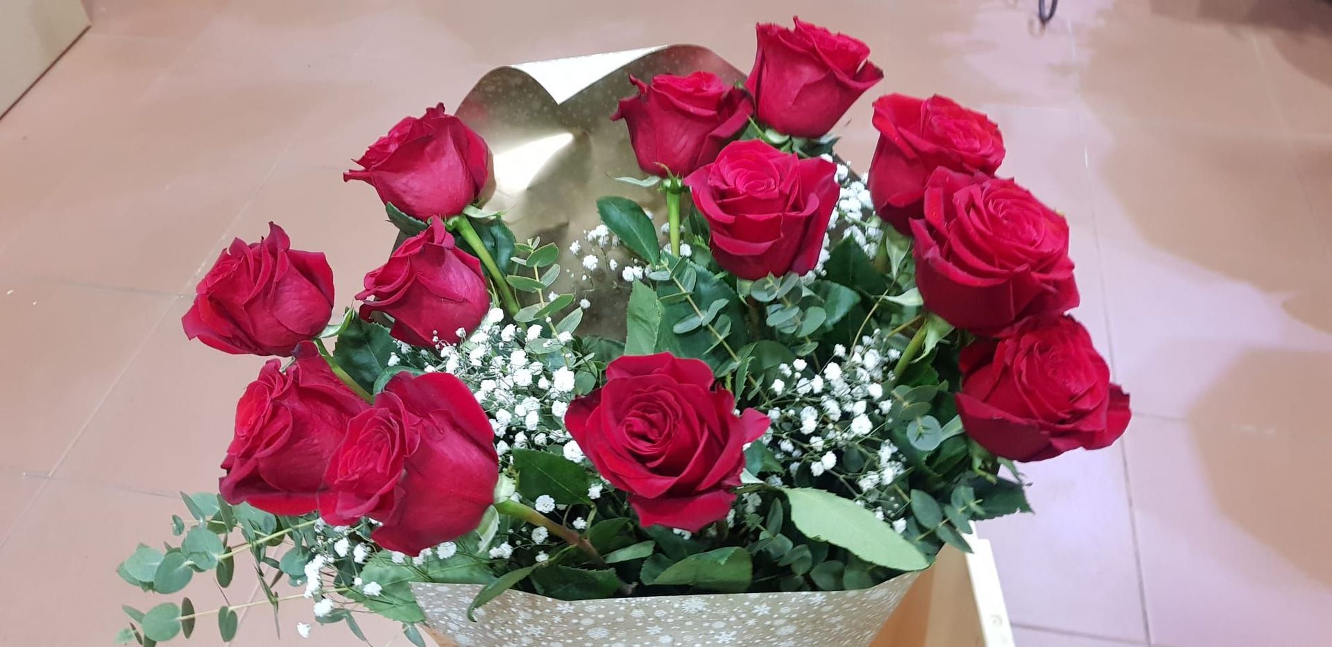 Un jarrón lleno de rosas rojas y flores de bebé sobre una mesa.