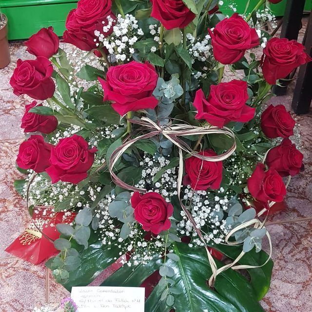 Un ramo de rosas rojas con aliento de bebé y vegetación.