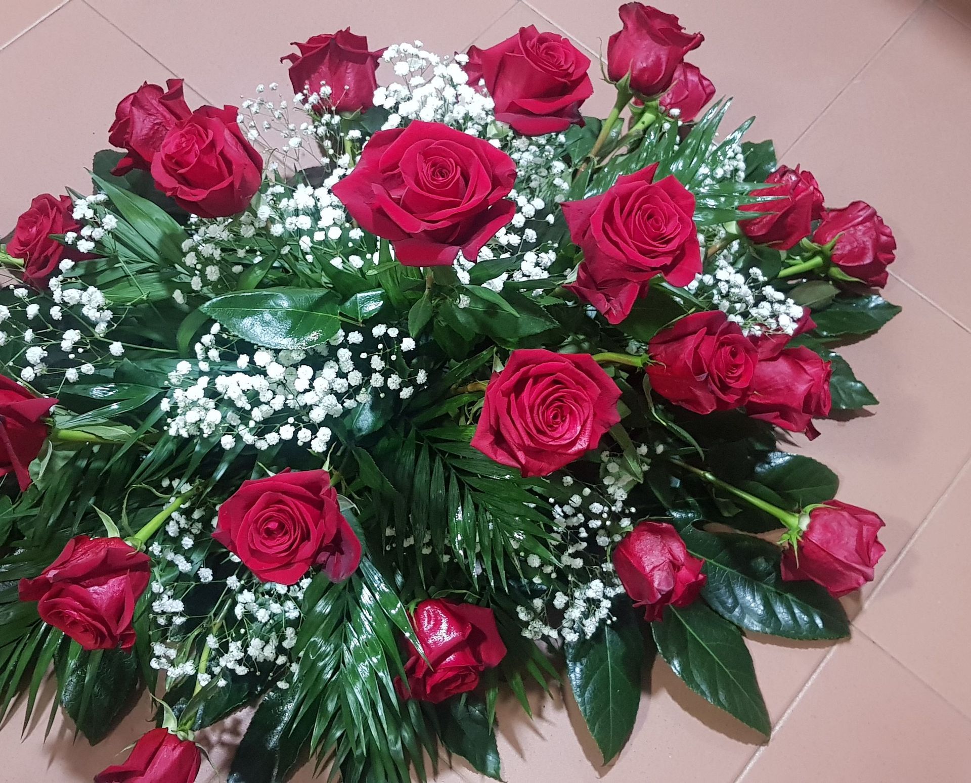 Un ramo de rosas rojas y flores de aliento del bebé en el suelo.