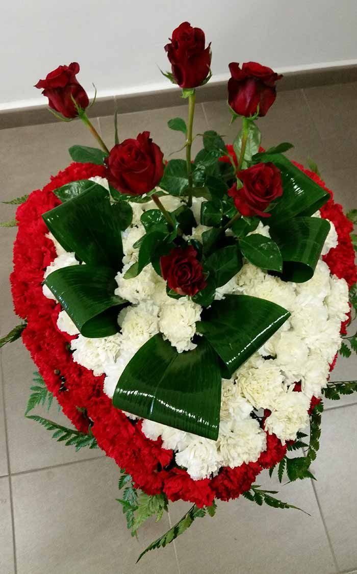Un arreglo en forma de corazón de flores rojas y blancas.