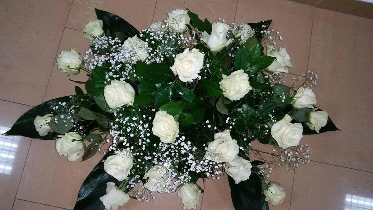 Un ramo de rosas blancas y flores de aliento sobre un suelo de baldosas.