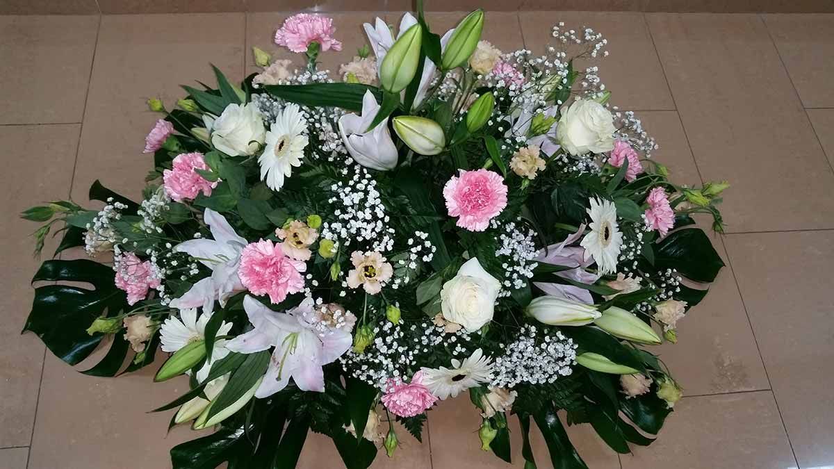 Un gran ramo de flores rosas y blancas reposa sobre un suelo de baldosas.