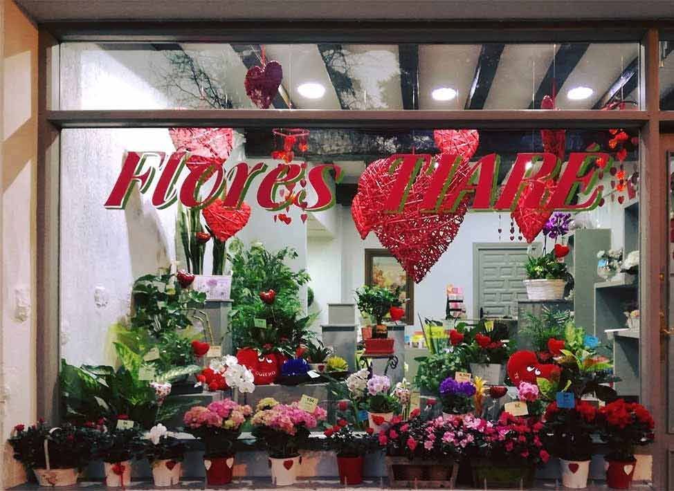 Un escaparate con flores y un cartel que dice flores