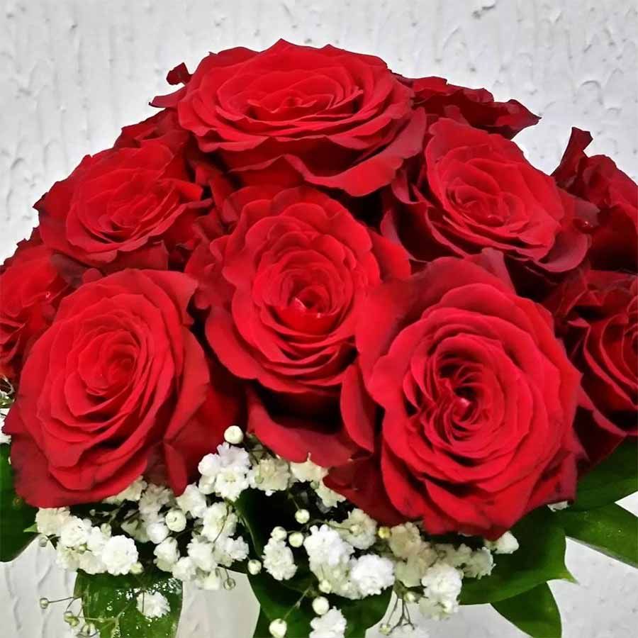Un ramo de rosas rojas con flores de aliento de bebé que las rodean.