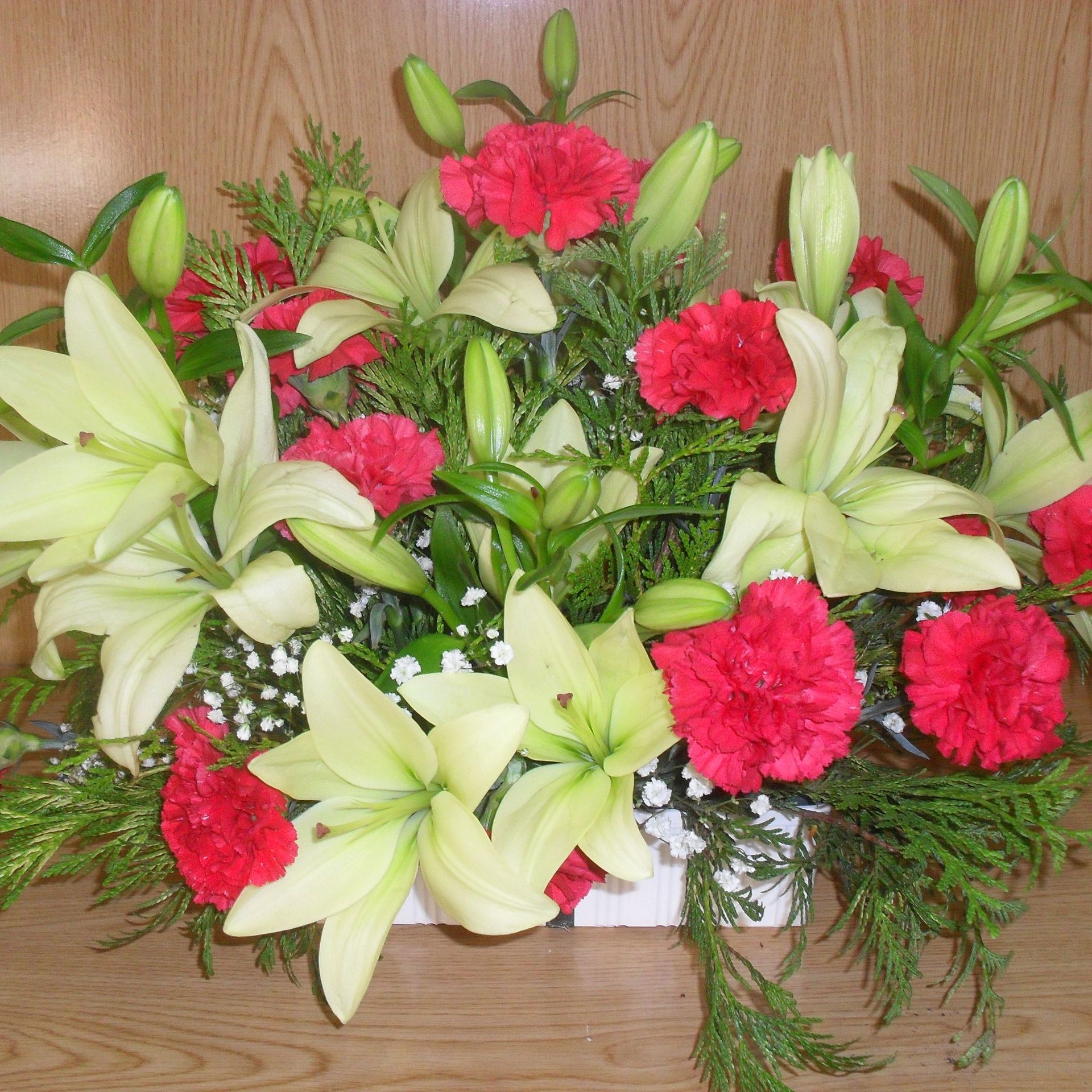 Un ramo de flores rojas y blancas en un jarrón blanco.