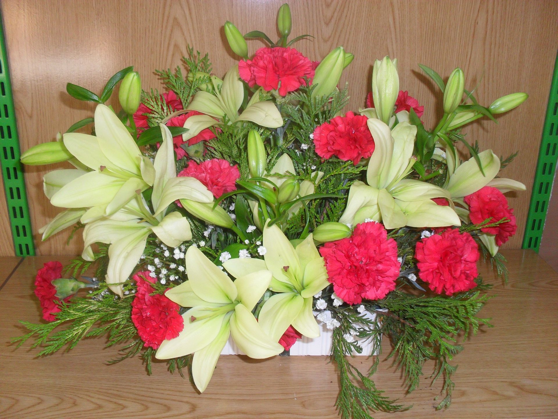 Un jarrón lleno de lirios blancos y claveles rojos