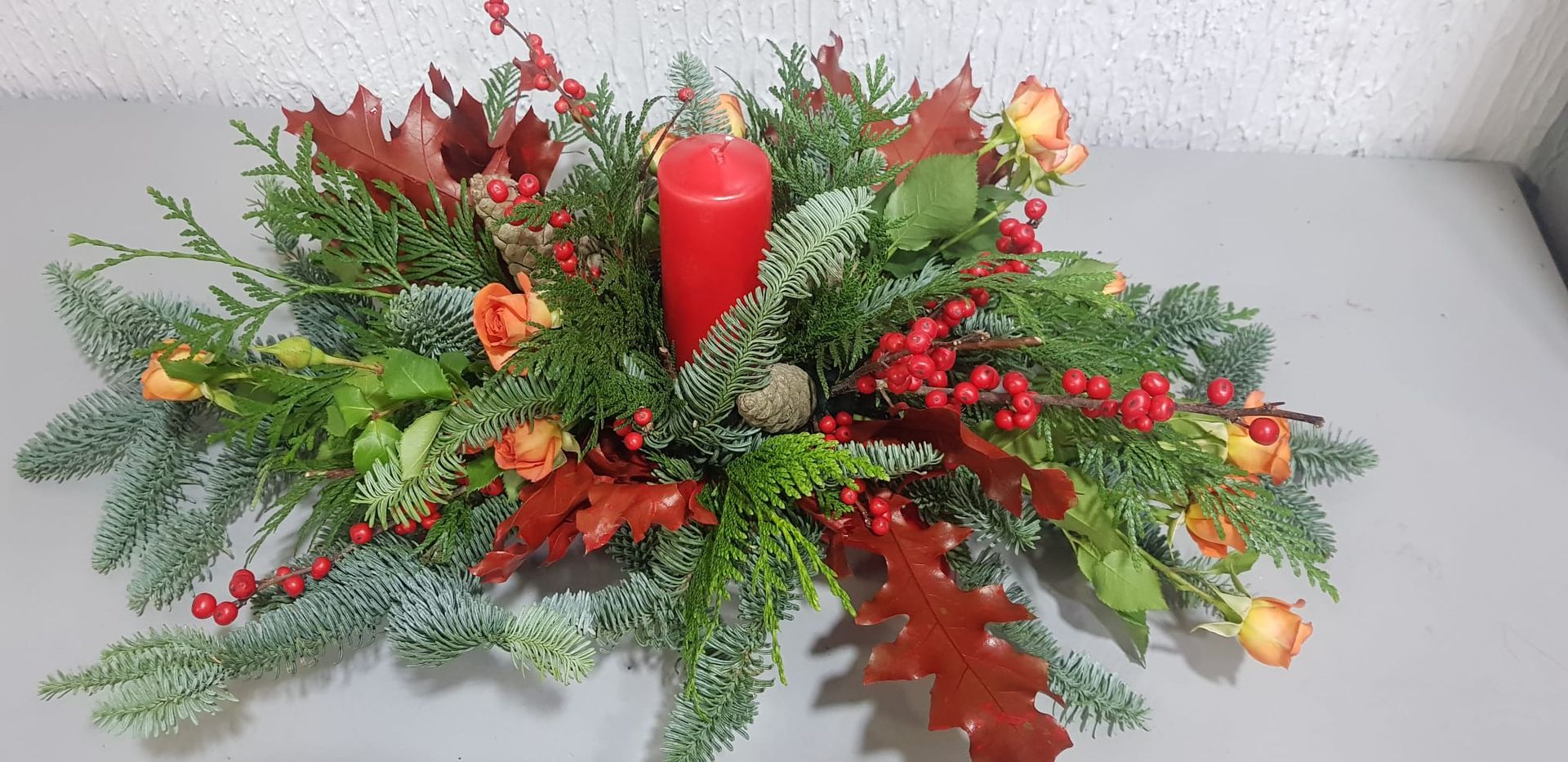 Un centro de mesa navideño con una vela roja en el medio.