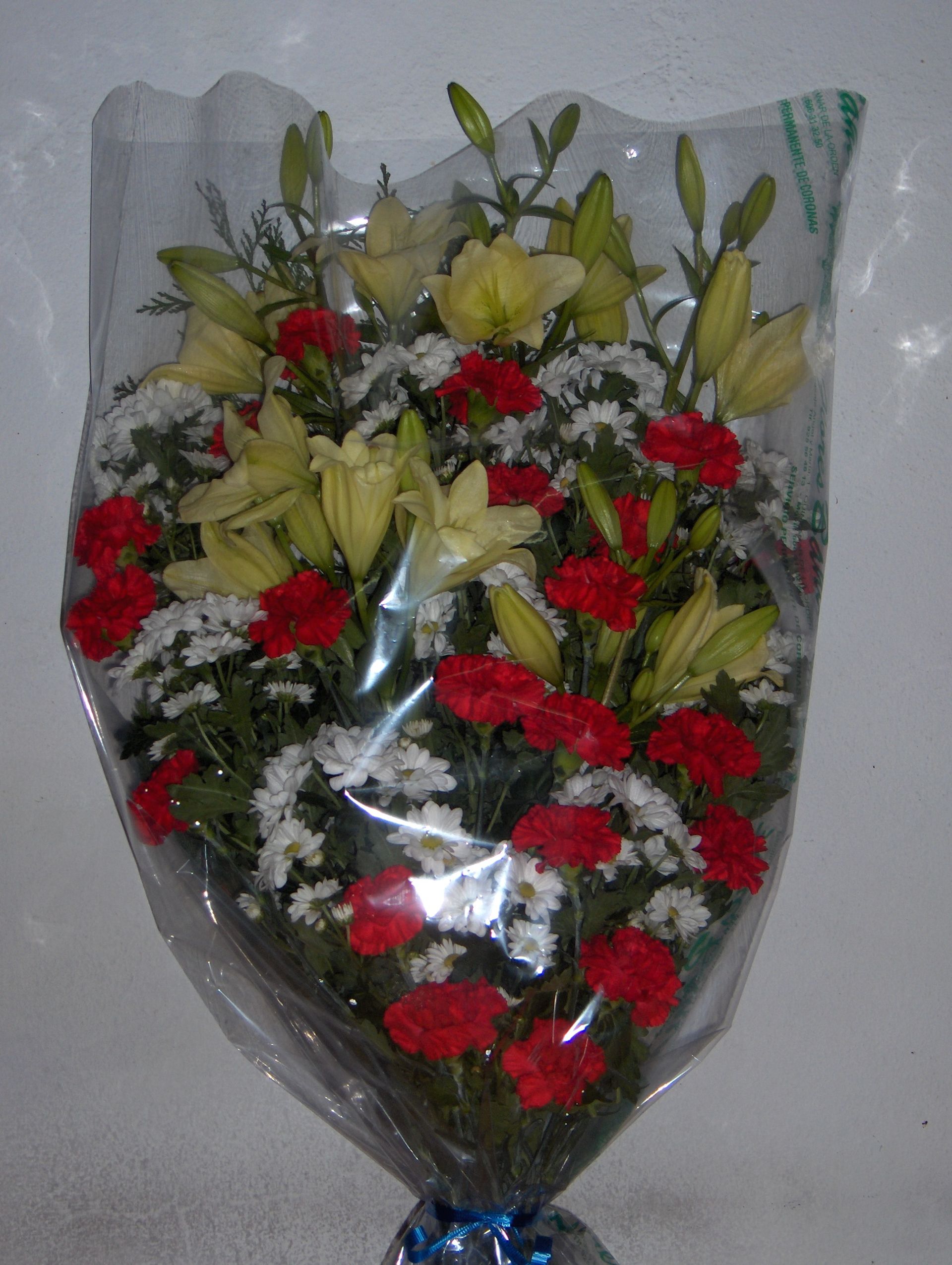 Un ramo de flores rojas y blancas envuelto en plástico.
