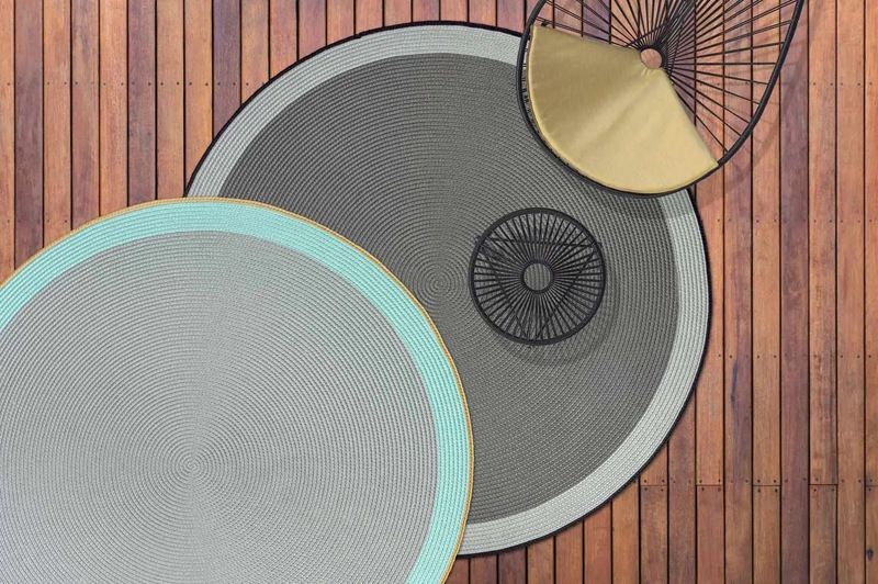 Trois tapis ronds sont posés sur une terrasse en bois.