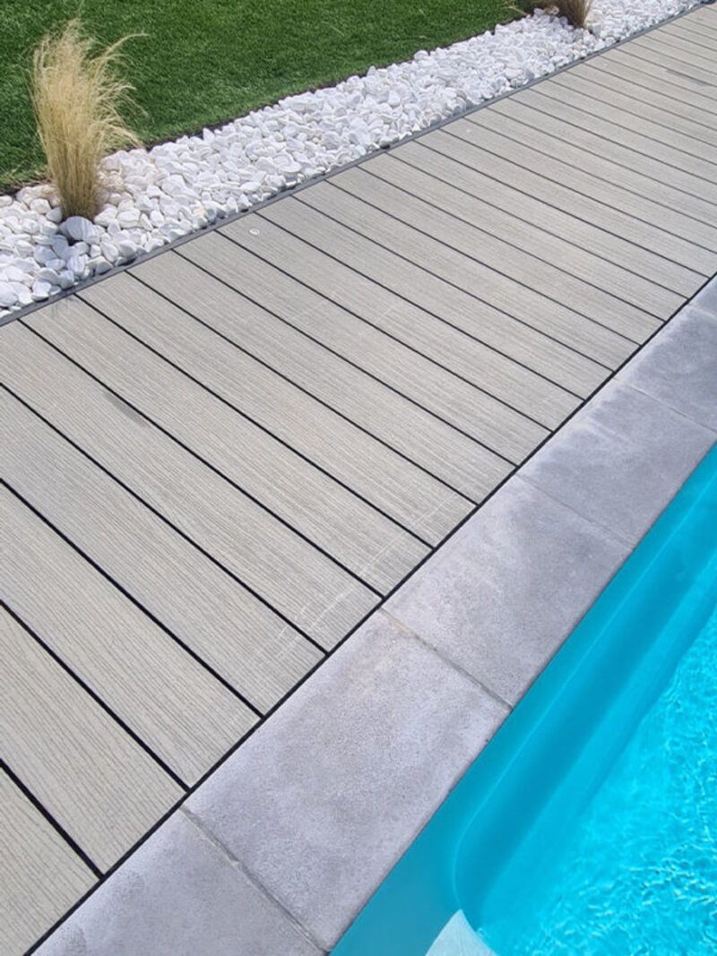 Une piscine avec une terrasse en bois à côté