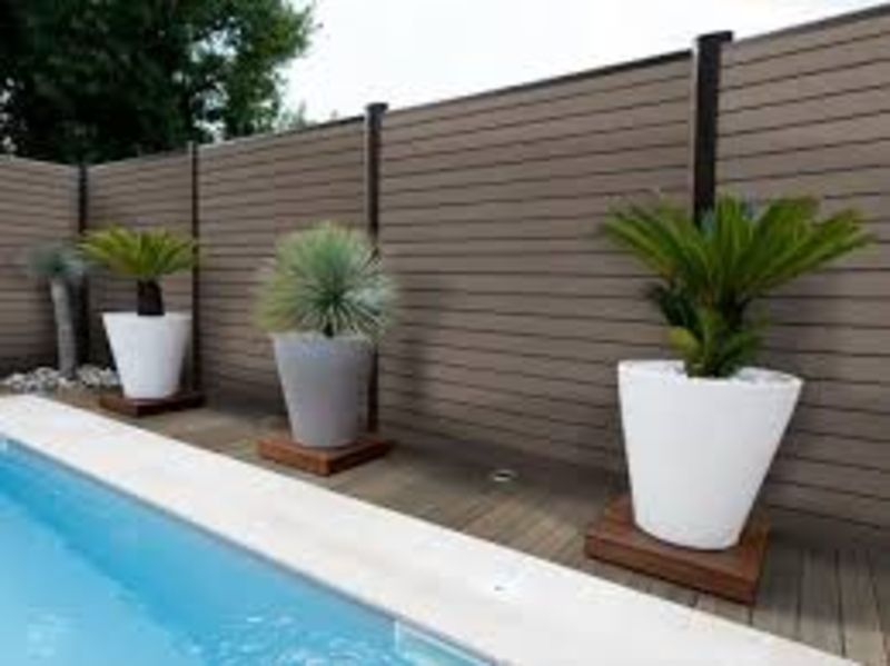 Une clôture avec des plantes en pot à côté d'une piscine.