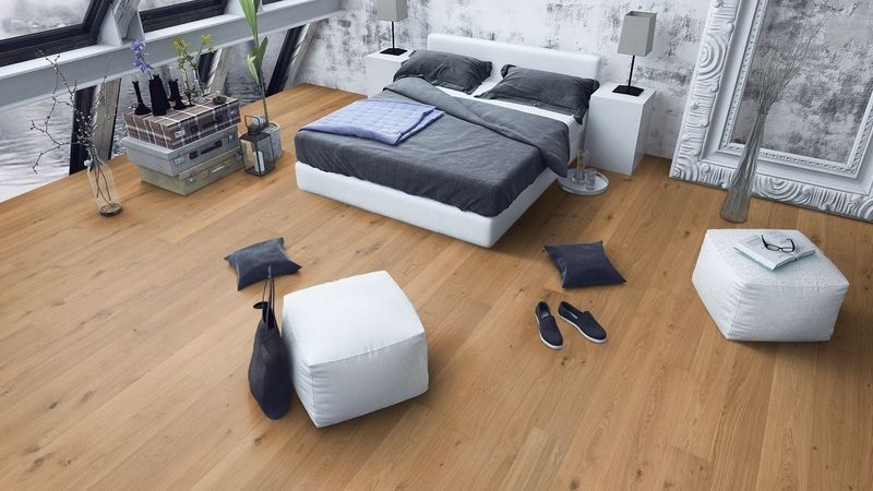 Une chambre avec un parquet et un lit.