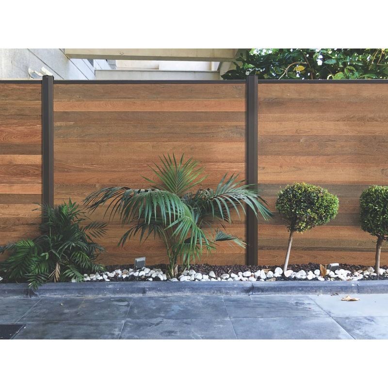 Une clôture en bois avec des arbres et des rochers devant.