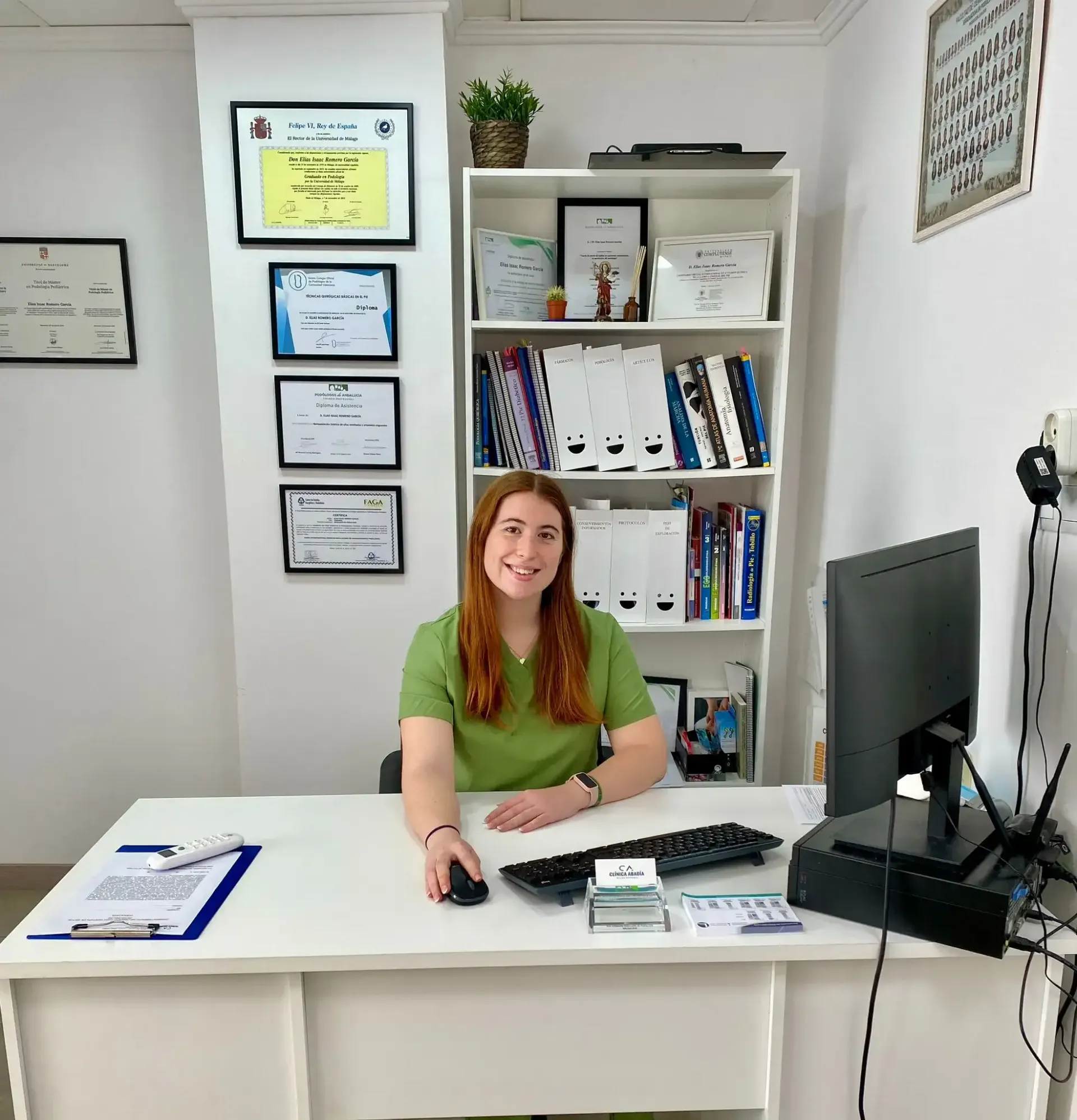 Pedicurista usando una herramienta rotatoria en el pie de un cliente; guantes rosas, blusa negra y jeans visibles.
