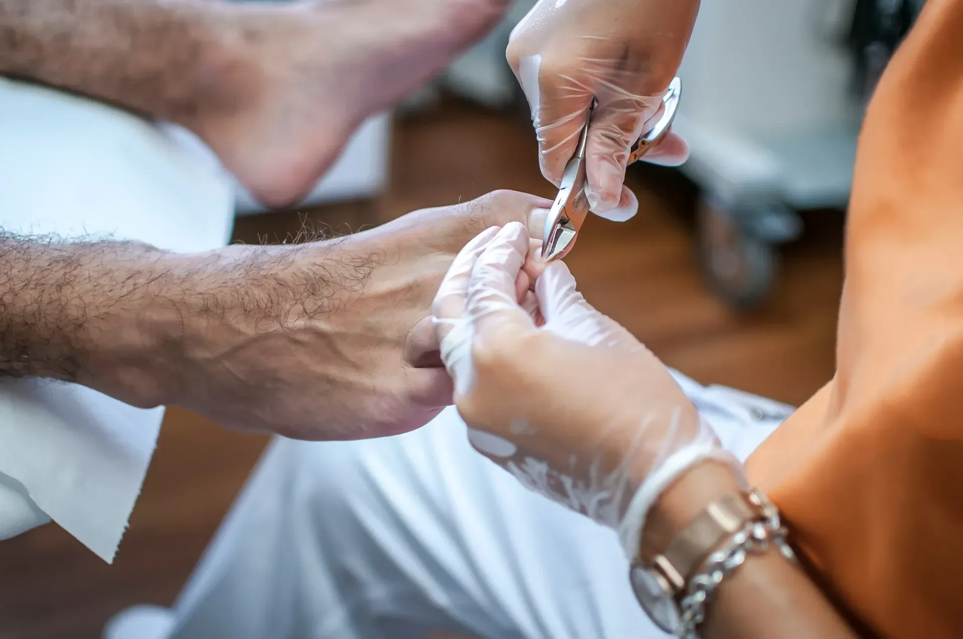 El pie de una persona siendo recortado con manos enguantadas y usando tijeras en lo que parece ser un entorno médico.