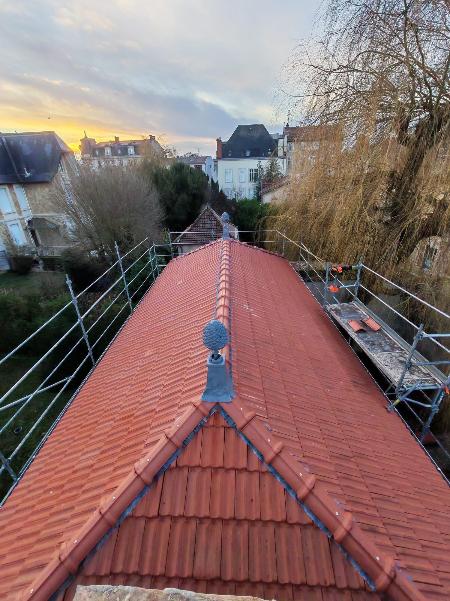 Toiture en tuiles rouges, pomme de pin ornementale et échaufaudages