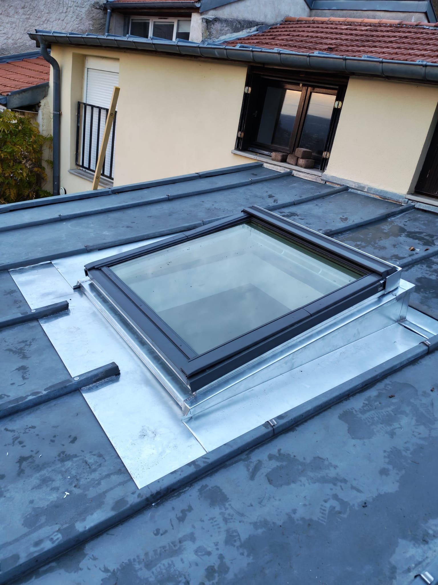 Puits de lumière rectangulaire à cadre noir sur un toit métallique. 